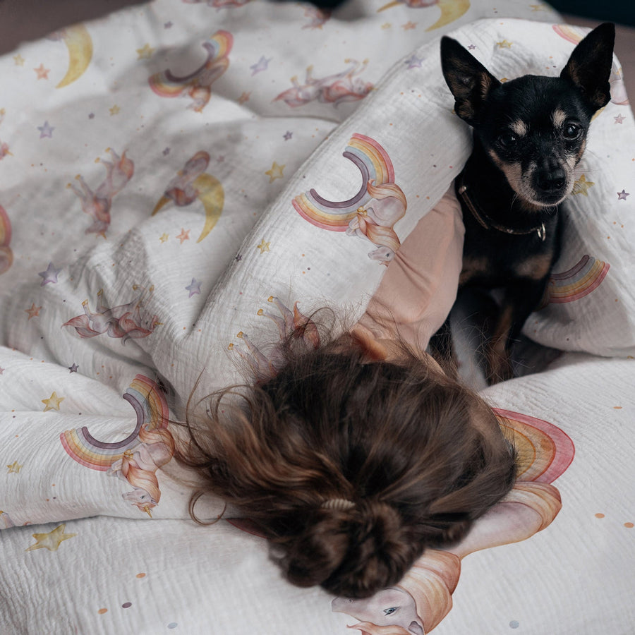 LESLIS Kinderbettwäsche „Regenbogen Einhorn" – Mädchen im Bett mit bezogener Bettdecke