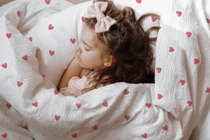 Mädchen kuschelt im Bett mit Herzchen-Kinderbettwäsche „Love"