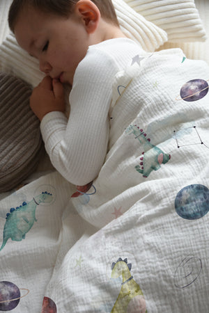LESLIS Kinderbettwäsche „Dino Galaxy" – Junge im Bett mit bezogener Bettdecke