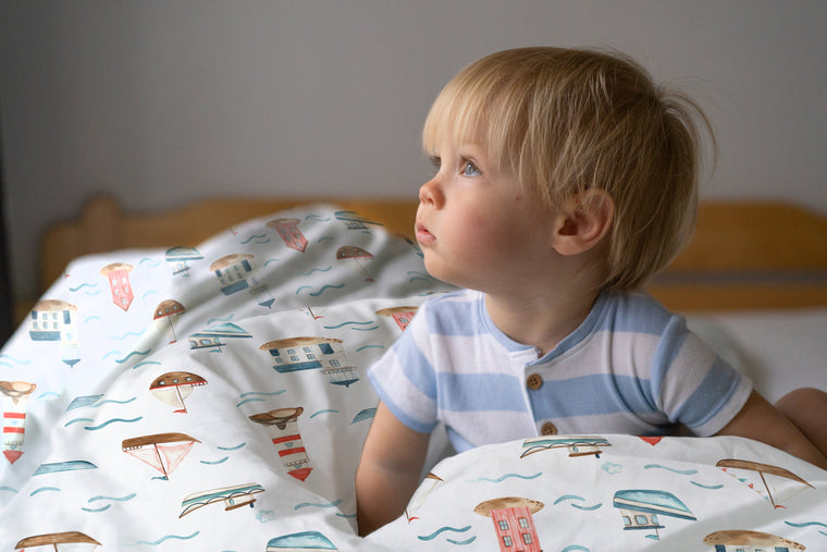 LESLIS Kinderbettwäsche „Am Meer" – Junge im Bett mit bezogener Bettdecke