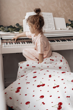 Kind im Bett mit Kinderbettwäsche „Kirschen", sommerliches Kirschen-Design