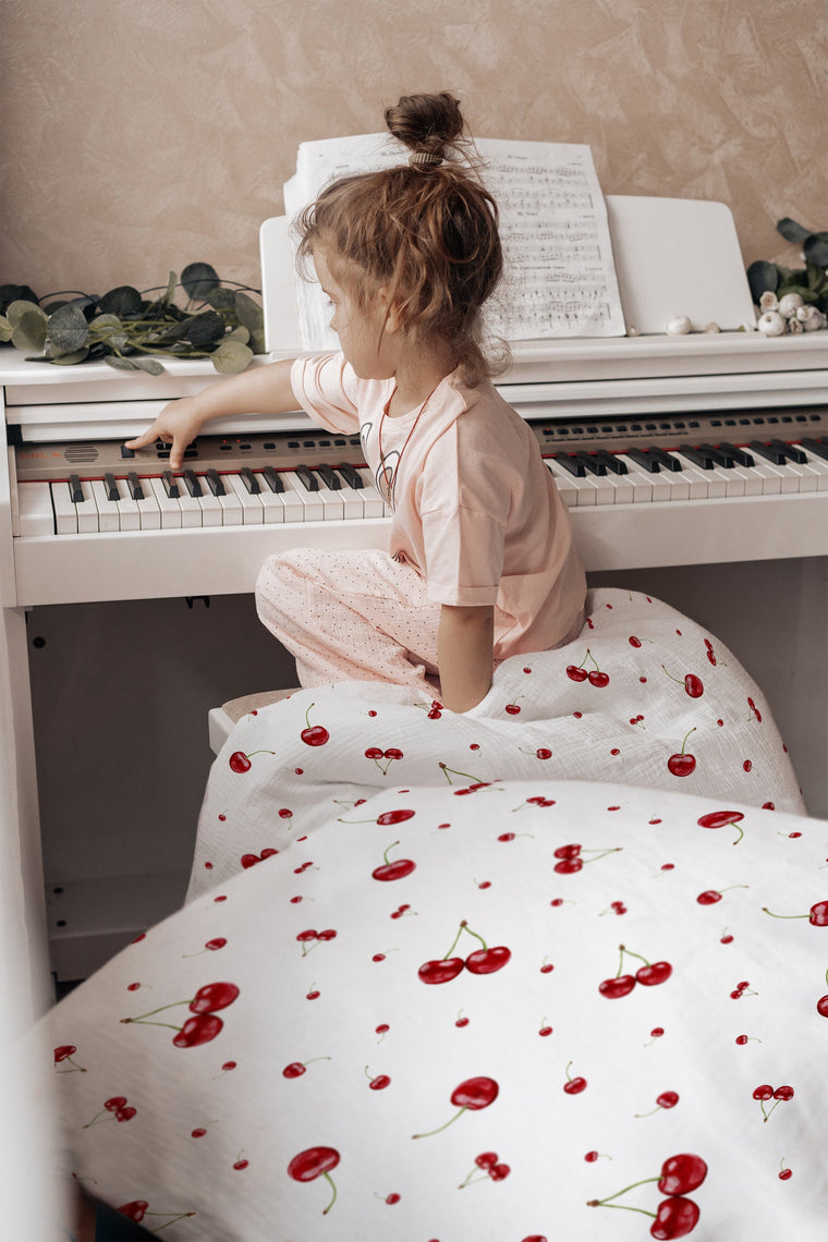 Kind im Bett mit Kinderbettwäsche „Kirschen", sommerliches Kirschen-Design