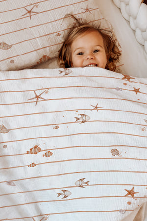 LESLIS Kinderbettwäsche „Kleine Seesterne" – Mädchen im Bett mit bezogener Bettdecke