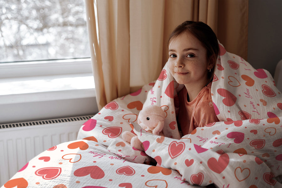 Mädchen im Bett mit Kinderbettwäsche „I love you", Herzen und Punkte in Rosa und Orange