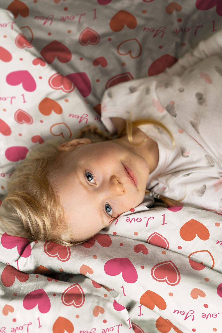 Kinderzimmer-Szene mit Mädchen und Kinderbettwäsche „I love you", Herzen-Motiv auf Baumwolle