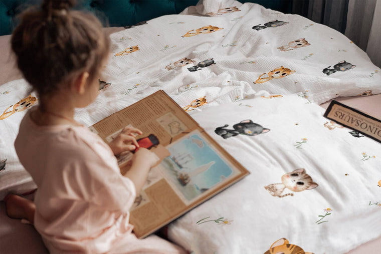 LESLIS Kinderbettwäsche „Katzen" – Mädchen im Bett mit bezogener Bettdecke
