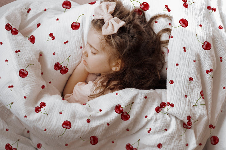 Mädchen kuschelt im Bett mit Kirschen-Kinderbettwäsche „Kirschen"