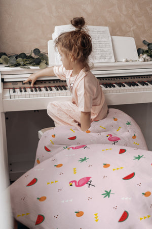 Mädchen lacht im Bett mit Flamingo-Kinderbettwäsche in Rosa