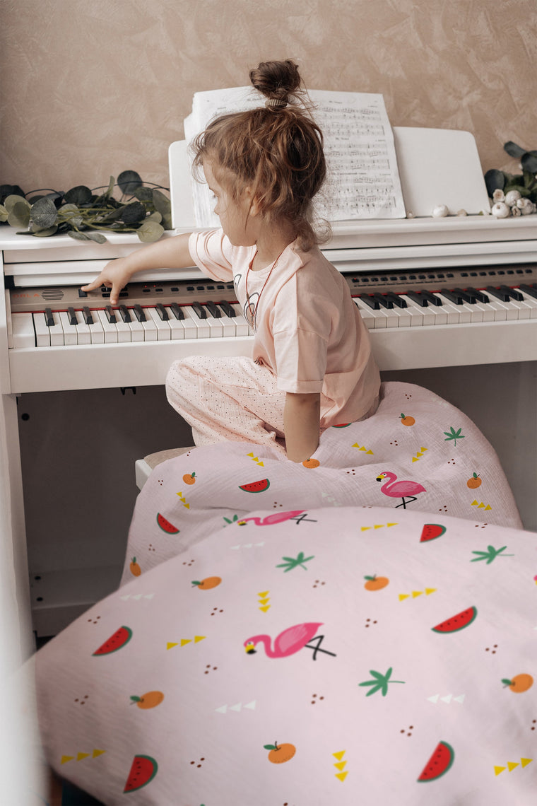 Mädchen lacht im Bett mit Flamingo-Kinderbettwäsche in Rosa