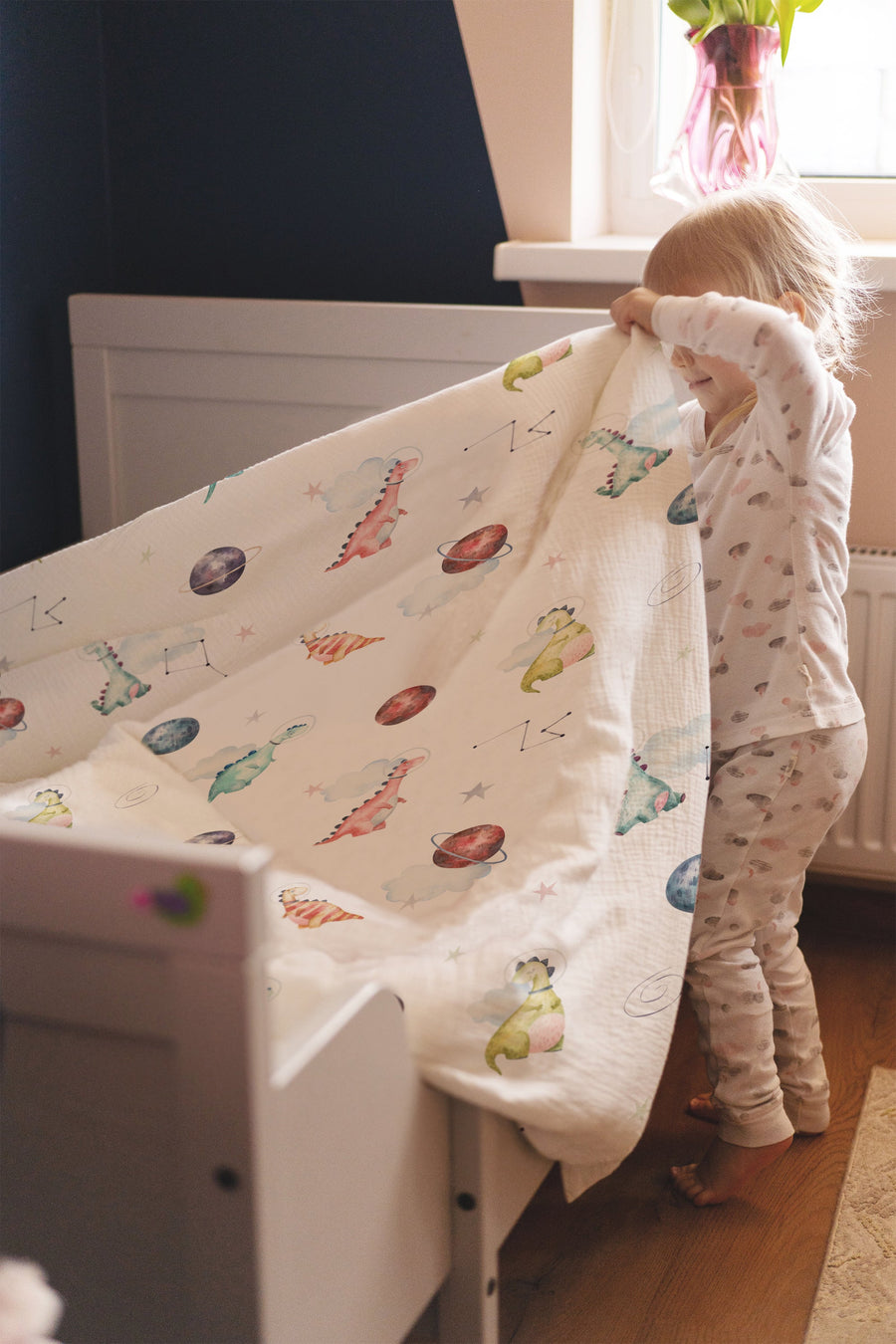 LESLIS Kinderbettwäsche „Dino Galaxy" – Mädchen im Bett mit bezogener Bettdecke