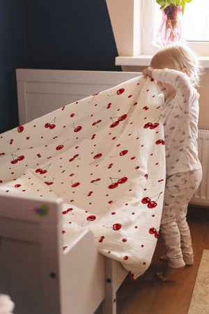 Mädchen entspannt im Bett mit Kirschen-Kinderbettwäsche „Kirschen"